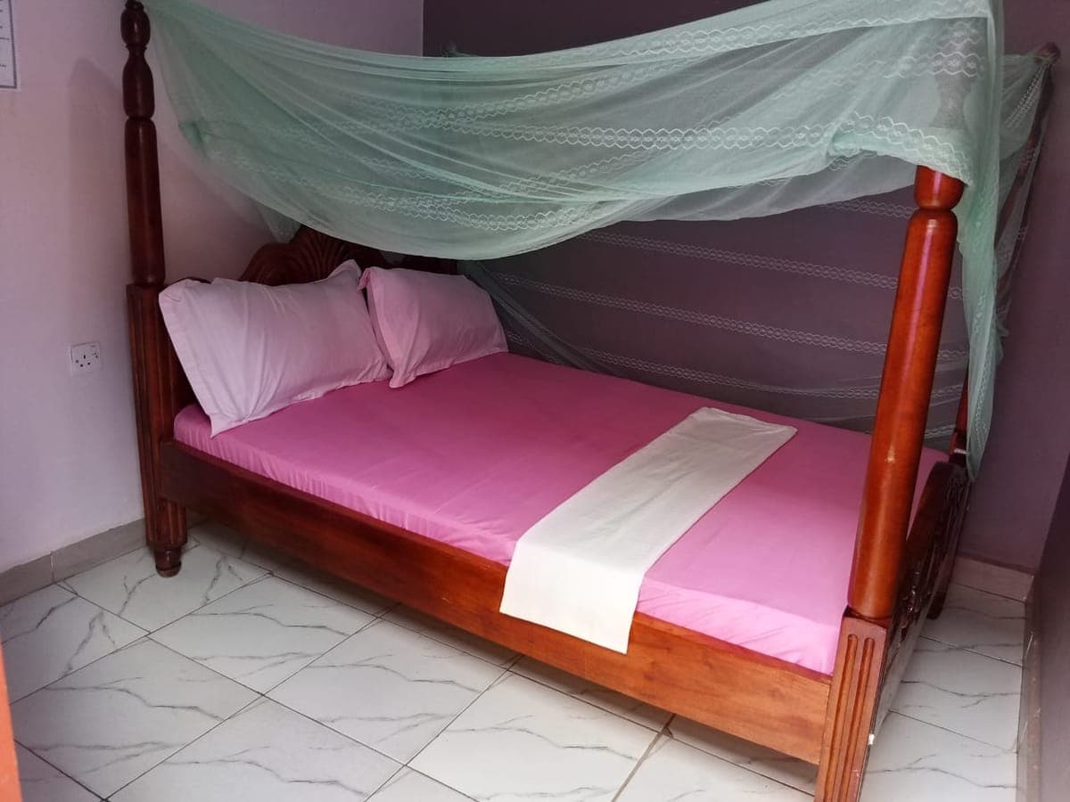 Freshly made double bed with a green mosquito net and white runner